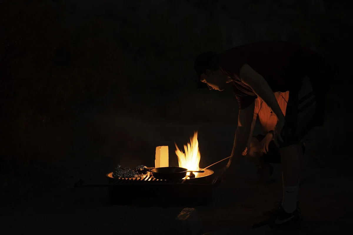 Foil packet dinners cooking over campfire coals — 2