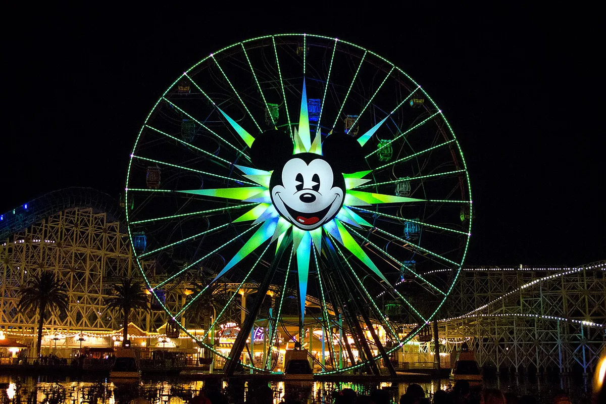 Mickey-shaped ice cream bar held up in front of a Disney park backdrop — 1