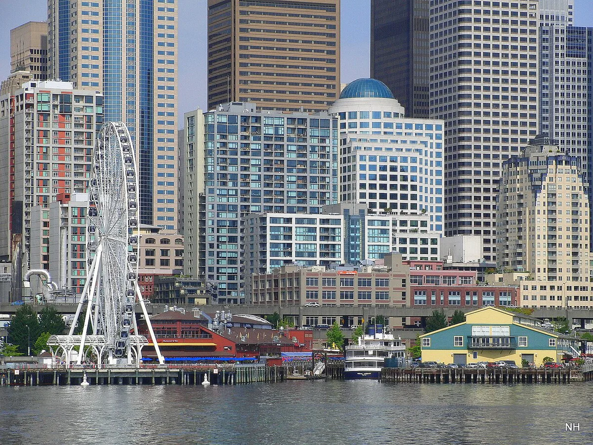 Pike Place Market sign and crowds with the Seattle waterfront beyond — 1