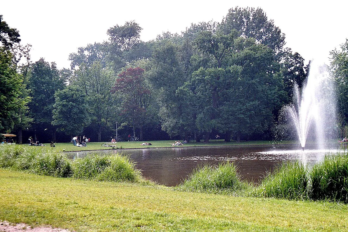 Families relaxing on the grass by a pond in Vondelpark Amsterdam — 1